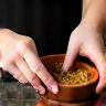 Hands mixing natural ingredients in a bowl during the handmade cosmetic process